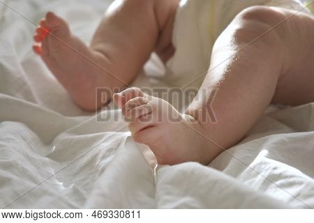 Baby Legs Close Up On White Blanket. Healthy Newborn Feet. Warm Sunlight. Beautiful Shot Of Infants 