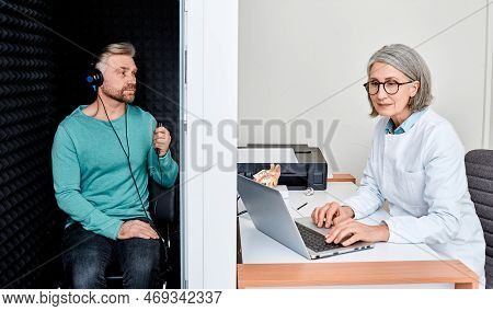 Audiological Exam. Audiologist Doing Hearing Check-up To Handsome Adult Man In Soundproof Audiometri