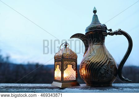 Glowing Moroccan Lantern, Golden Ornamental Arabic Coffee Pot Dallah. Outdoor Blurred Blue Evening S