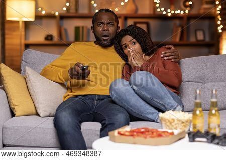 Frightend Black Couple Watching Horror Movie At Home
