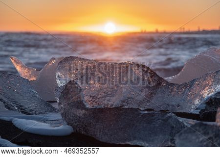 Diamond Beach In Iceland. Icebergs Shining On Black Volcanic Sand At Sunset. Clear Ice Crashed By Oc