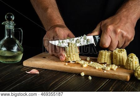 Hands Of A Cook With A Knife Cut Boiled Corn Kernels. Maize Is An Excellent Dietary Breakfast Or Lun