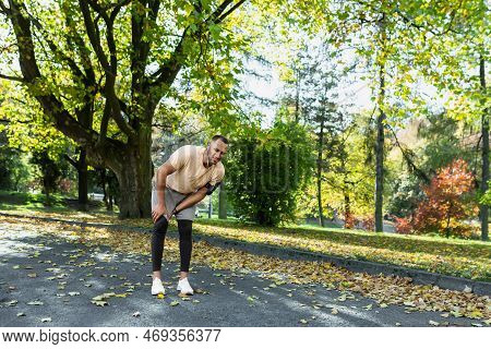 Runner Injured His Leg While Jogging In The Park Near The Trees, Hispanic Man Has Muscle Spasm Massa