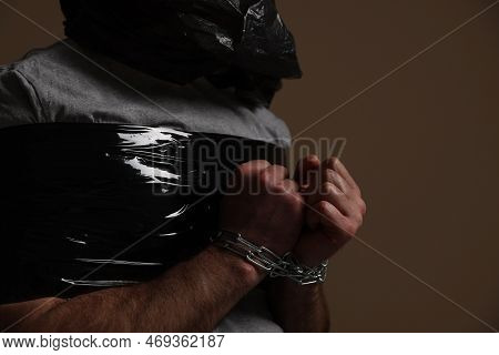 Victim Tied With Duct Tape And Chains On Dark Background, Closeup. Hostage Taking