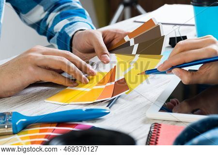 Interior Designer Choosing Colors From Swatches At Wooden Desk. Office Workplace In Design Studio. S