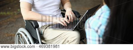 Man In Wheelchair And Woman Work Remotely While Sitting In Park. Freelance For People With Disabilit