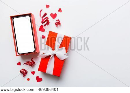 Opened Gift Box With Ribbon And Phone On Color Background, Top View. Blank Open Box Packaging Mockup