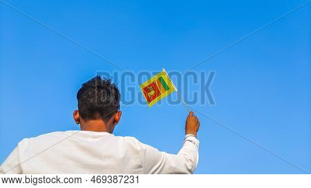 Boy Holding Sri Lanka Flag Against Clear Blue Sky. Man Hand Waving Sinhalese Flag View From Back, Co