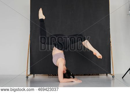 Young Professional Gymnast Woman Standing On Splits. Pretty Brunette Girl Doing An Elbow Stand. Fema