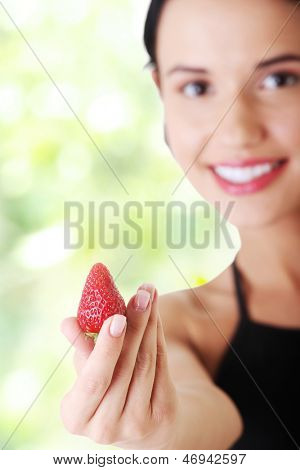 Giovane donna felice con fragola. Focalizzata su strowberry.