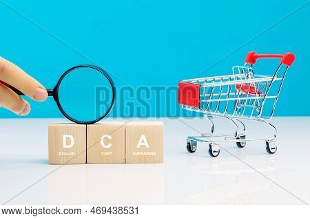 Magnifying Glass In Woman's Hand And Dca Word On A Wooden Cube In Idea Dollar Cost Averaging Investm