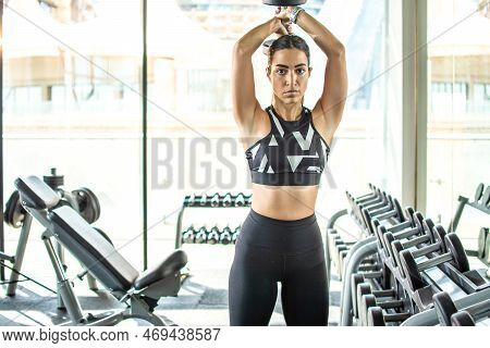 Fit Sportswoman Exercising With Weights In Gym. Active Sporty Woman Holding Up Dumbbell Over Head.