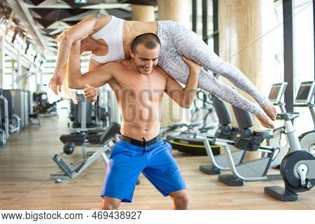 Fit Man Lifting Sporty Woman Up At Gym.