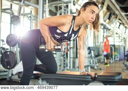Attractive Sporty Woman Flexing Muscles With Dumbbell In Gym.