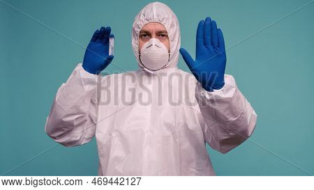 A Male Doctor In Protective Overalls And A Mask Holds An Ampoule With A Vaccine In His Hands Shows S