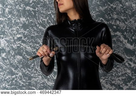 Beautiful Woman Mistress In Latex Bodysuit Holds A Whip In Her Hands.