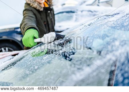 Teenager  Cleans Car After A Snowfall, Removing Snow And Scraping Ice