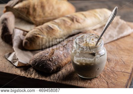 Rye Sourdough Ripened In A Jar Together With Fresh Bread On A Cutting Board.