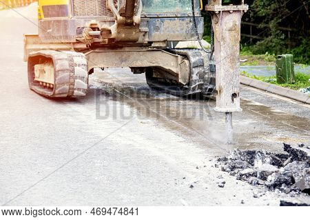 Excavator With Hydraulic Jack Hammer  Breaking Asphalt In Preparation For Drainage Works Close Up An