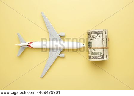 Flatlay Picture Of Toy Aeroplane, Toy Camera, Luggage With Roll Fake Money On Yellow Background. Exp