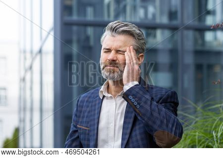 Sick And Sad Mature Businessman Outdoors Sitting On Bench On Office Building Background, Senior Boss