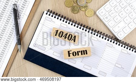 1040 A Form Word Written On A Wooden Block On Planner With Coins, Clipboard And A Calculator