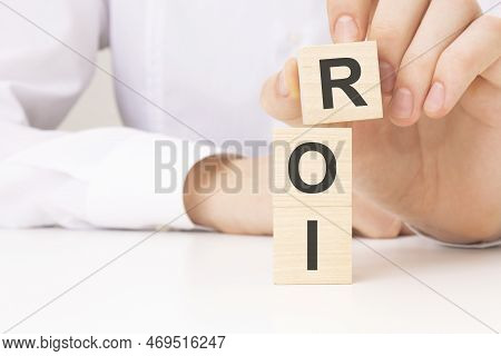 Hand Holding Wood Cube Block With Roi Text. Financial, Management, Economic, Business And Time Conce