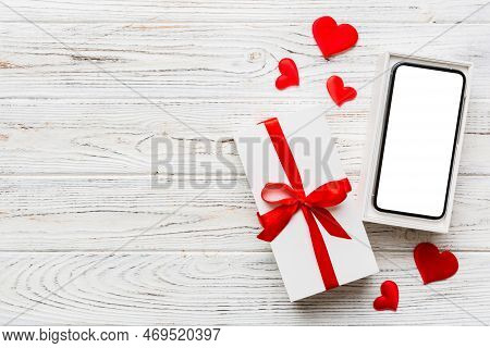 Opened Gift Box With Ribbon And Phone On Color Background, Top View. Blank Open Box Packaging Mockup