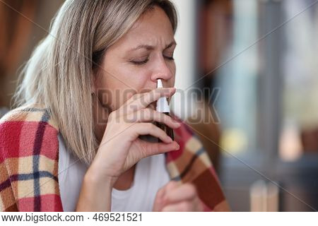 Woman With Illness, Covered In Blanket, Uses Nasal Spray Close-up. Cold Season And Weak Immunity Con