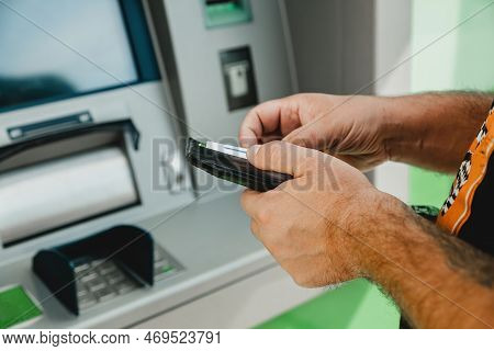 Man Atm Card. Atm Insert Card. Man Putting Credit Card In Atm Machine While Holding Wallet