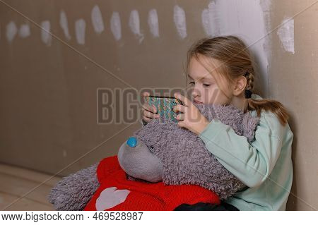 A Sad Nine-year-old Girl, She Is Sitting In A Room In The Attic Without Repairs On The Floor, She Hu