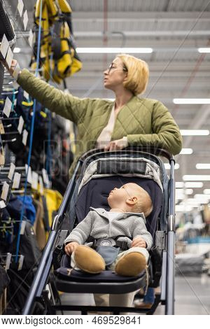 Casualy Dressed Mother Choosing Sporty Shoes And Clothes Products In Sports Department Of Supermarke