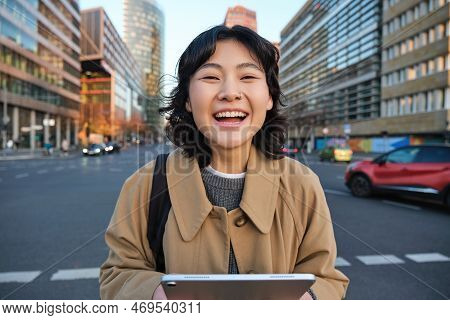 Portrait Of Asian Girl Student, Stands In City Centre With Cars On Busy Street, Holds Digital Tablet