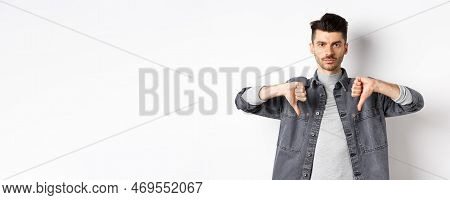 Very Bad. Serious Man Showing Thumbs Down And Look At Camera With Pokerface, Telling No, Disapprove 