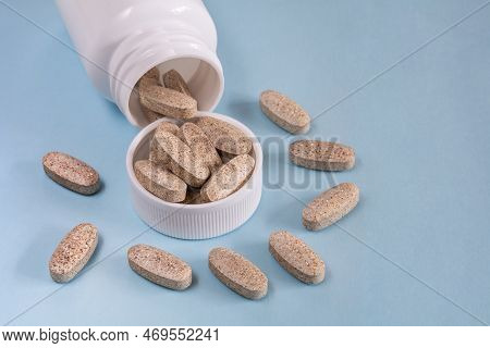 Oblong Tablets Spilled From A Bottle On A Blue Background