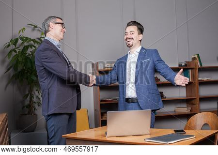 Two Happy Cherrful Businessman In Suit Smiling, Laughing And Making Handshake In Office, Business Su