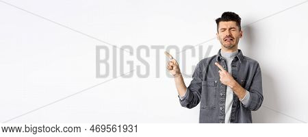 Sad Crying Man Pointing Fingers Left At Logo, Sobbing And Whining, Being Jealous Or Upset, Standing 