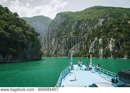 View From The Ferry On Lake Komani. A Tourist Boat Overtakes The Car Ferry On Komani Lake In The Din