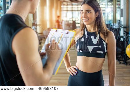Personal Trainer And Client Looking At Progress At The Gym. Athletic Man And Woman Wearing Sportswea