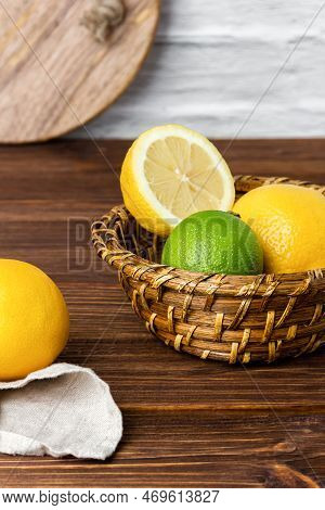 Lemons And Limes In Basket On Wooden Table. Side View Of Fresh Citrus.