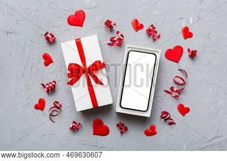 Opened Gift Box With Ribbon And Phone On Color Background, Top View. Blank Open Box Packaging Mockup