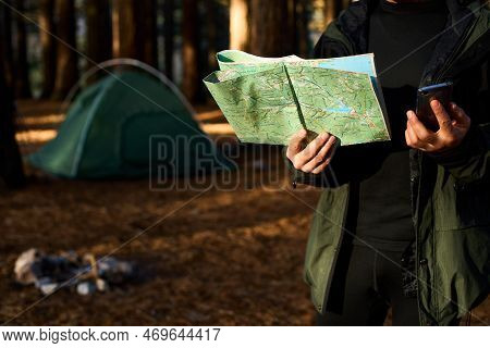Adult Hiker With Backpack Using Mobile Phone And Map In Forest Near His Tent. Hiking Elderly Man In 