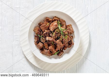 Seared Juicy New York Strip Steak Bites With Butter, Rosemary And Garlic In Bowl On White Wood Table