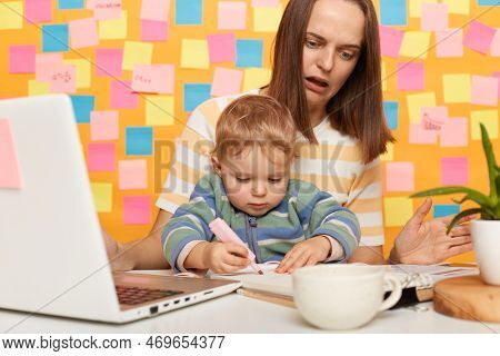 Portrait Of Shocked Woman With Brown Hair Wearing Striped T-shirt Sitting At Table Standing Against 