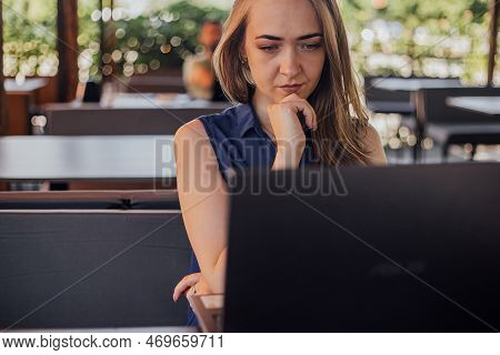 A Girl Sits On A Summer Terrace And Works At A Laptop. Freelance. Selfeducation. The Concept Of Remo