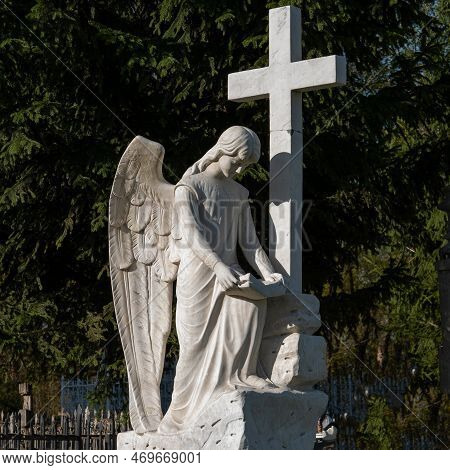 Beautiful Sad Angel With Cross. Fragment Of Ancient Stone Statue With A Sweet Expression That Looks 