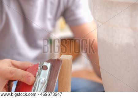 A Man Grinds Wood With Sandpaper. The Process Of Grinding A Piece Of Wood With Bar With Sandpaper. S