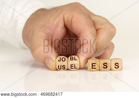 On A Reflective White Surface In The Hands Of A Man Are Cubes With The Inscription - Jobless To Usel