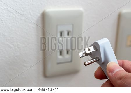 A Japanese Wall Socket Without Earth Post. 3 Pins Power Plug Holding By Hand.