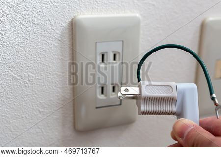 A Japanese Wall Socket Without Earth Post. 3 Pins Power Plug Connected To A Travel Adapter.